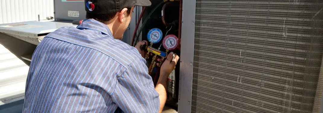 HVAC technician servicing a condenser unit in Williamsburg